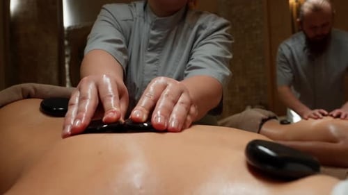 Relaxing Hot Stone Back Couples Massage Therapy in Tranquil Spa Setting with Professional Masseurs