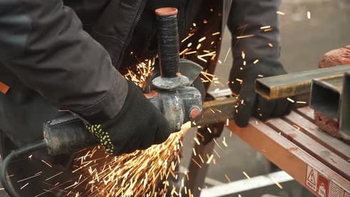 Arbeiter, der Metallrohre mit einem Winkelschleifer schneidet. Helle Funken und
Blitze