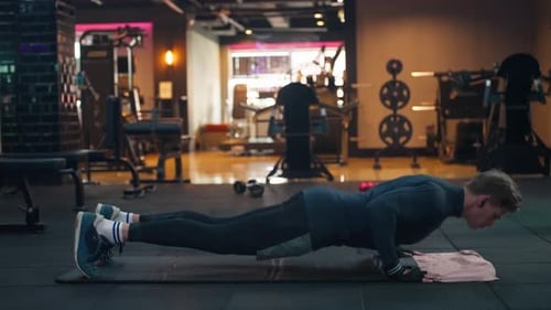 Muscular blond man doing push ups in the gym