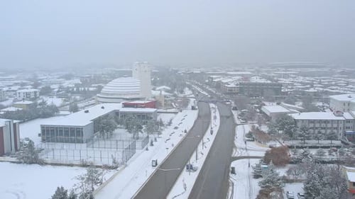 a snow gently falls over the city, the world below transforms into a quiet, cinematic landscape