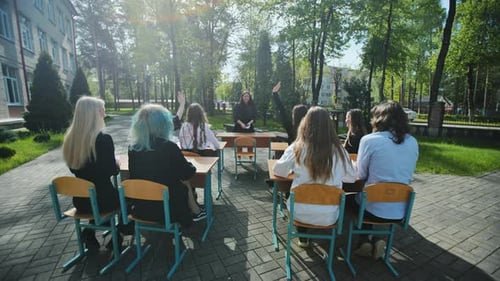 High School Students Raising Hands to Answer Teacher's Question During an Outdoor Class on a Sunny
