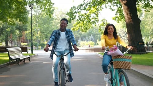 Young Couple Enjoying a Fun Bike Ride in the Park on a Sunny Day