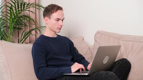 Young Adult Works on Laptop at Home
