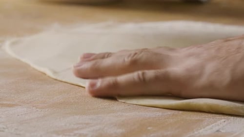 Hands Rolling Dough with Rolling Pin Close-up