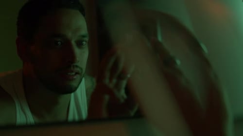 Tense Man in Low Light, Contemplating His Reflection in Mirror