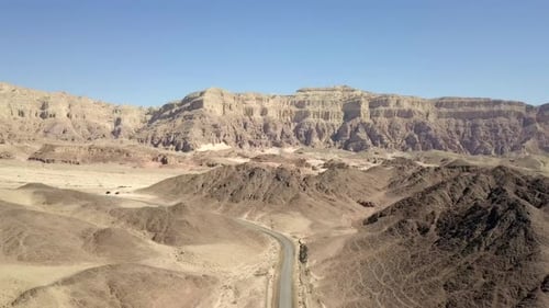 Empty desert road with mountains and blue sky in the background
