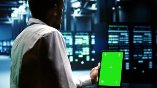 Afroamerikanischer Ingenieur verwendet Greenscreen-Tablet zur Serverinspektion mit Mainframes