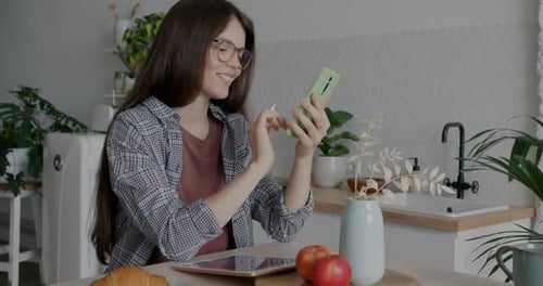 Woman Using Phone at Kitchen Table