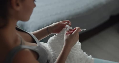 Woman Crocheting White Blanket on Couch Indoors