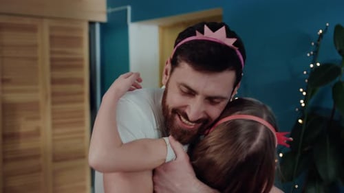 Smiling Father Hugging Daughter Wearing Crowns