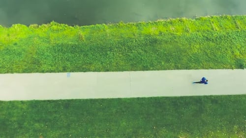 Athlete at the Lake Running in Green Nature on Asphalt Path Action