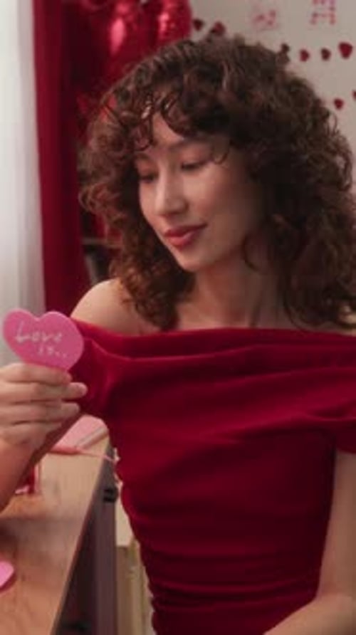 Smiling Young Woman Holds Pink Heart Indoors