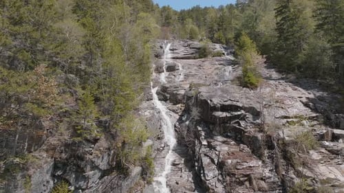 Large high mountain waterfall in the green forest. Aerial view.