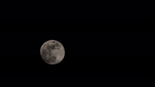 Nearly full moon rising with wispy cloud passing over in early spring
