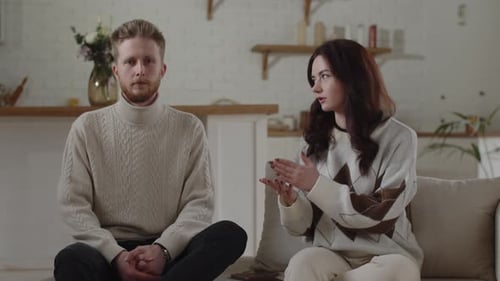 Young Couple Talking on Couch Indoors