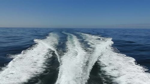 wake of water seen from behind of fast moving motor boat in a clear sky day,Blue sea , water surface