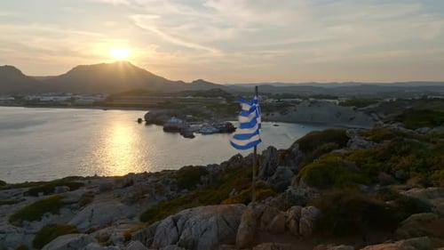 Aerial view orbiting a Greece flag, sunny evening in Kolymbia, Rhodes, Greece