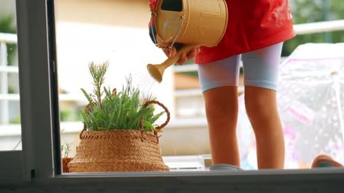 Child Watering Plants with Watering Can on Balcony