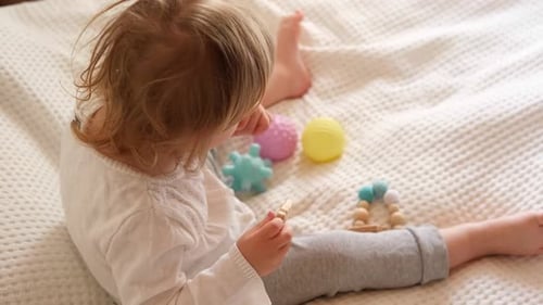 Child Plays with Toys on White Bed