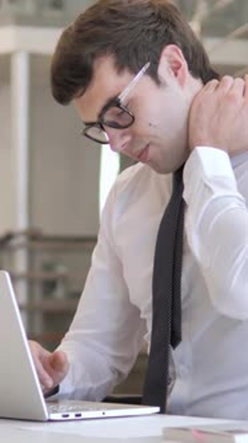 Man Massaging Stiff Neck While Using Laptop