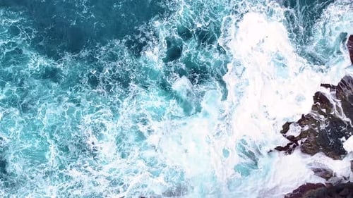 Les vagues s'écrasent sur un rivage rocheux dans un paysage côtier plein de mouvement
