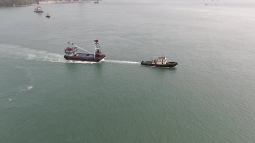 Tugboat pulling a small Barge in Hong Kong bay, Aerial view.