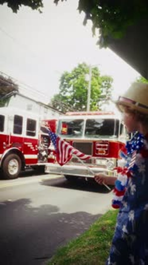 Boy Waves Flag As Fire Trucks Pass