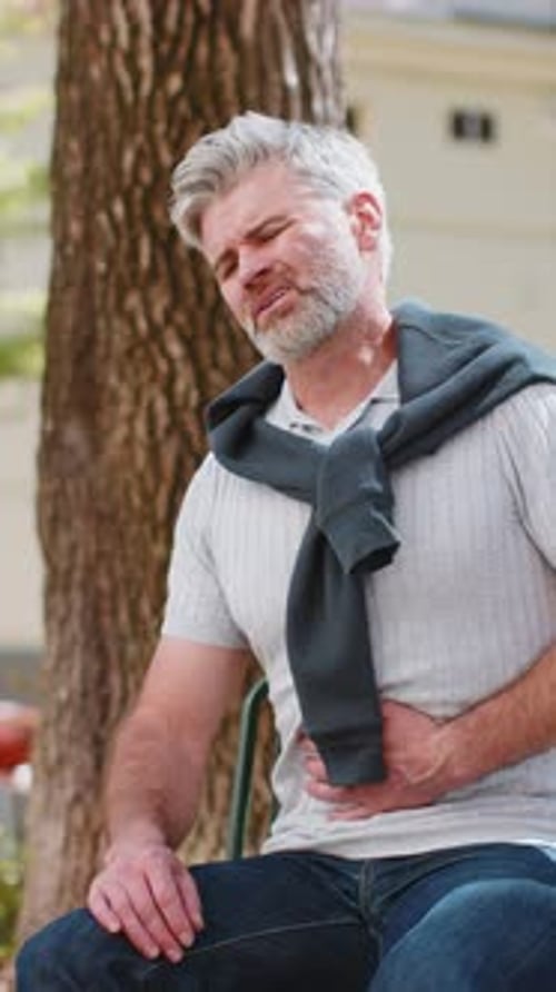 Man Experiencing Stomach Pain in an Urban Park
