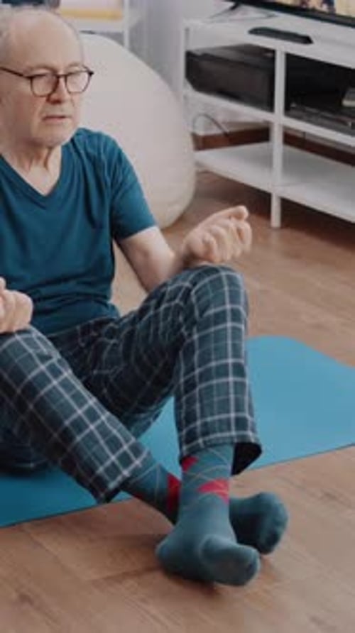 Senior Man Sitting on Yoga Mat at Home