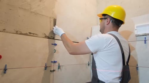 Construction Worker Installing Tiles with Laser Level