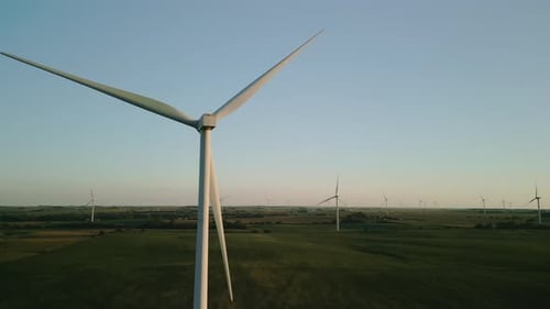 Wide Aerial Drone View of a Wind Farm Park with Wind Turbines Standing in a Wheat Field at Sunset