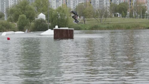 Athlete Wakeboarding and Jumping in Urban Lake Park
