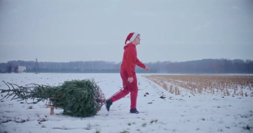 Homme souriant tirant un traîneau avec arbre de Noël sur un paysage enneigé