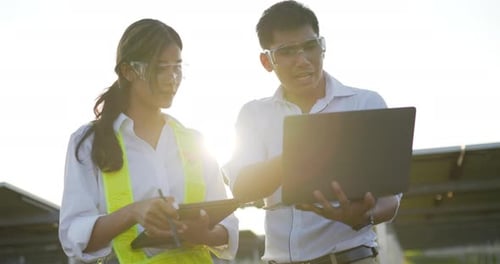 Junge Ingenieure, Mann und Frau, arbeiten mit Laptop und Tablet in einer Solarstation