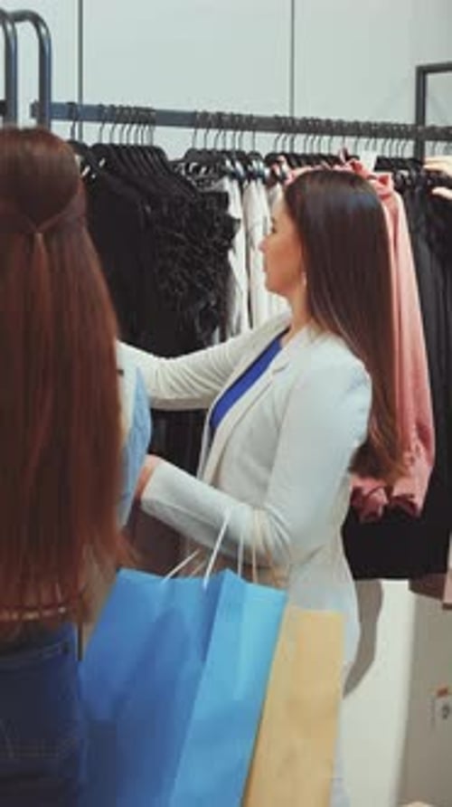 Women browse clothing rack inside of retail store