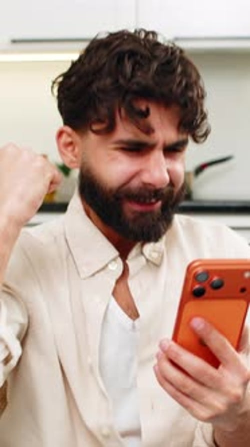 Happy Man Cheering While Looking at Mobile Phone