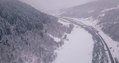 Drone rising up showing the beauty of winter in countryside with a road passing by and trees on both