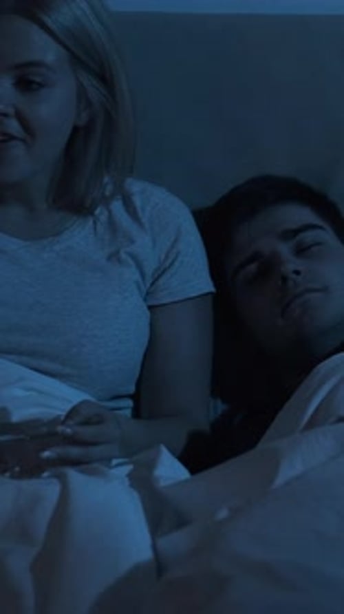 Woman Eating Popcorn in Bed with Man at Night