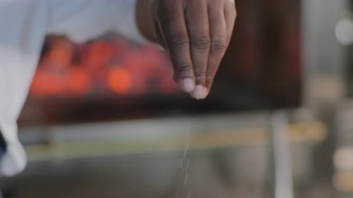 Black Chef Sprinkling Salt with her fingers