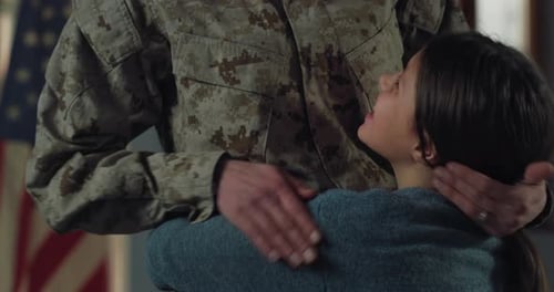 Girl Hugs Soldier in Front of American Flag