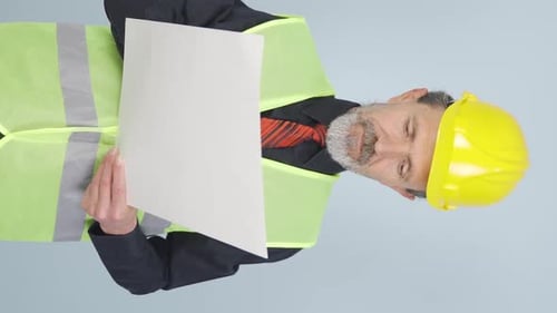 Vertical video of The old engineer examines the project in his hands.