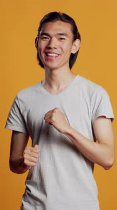 Vídeo vertical de homem asiático mostrando movimentos de dança legais na câmera