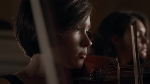 Women Playing Violin in Dark Room