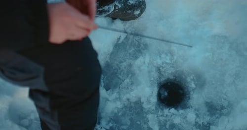 Fischer, der im Winter Fische in einem Eisloch in einem gefrorenen Fluss oder See fängt, Nahaufnahme der Hände Prores