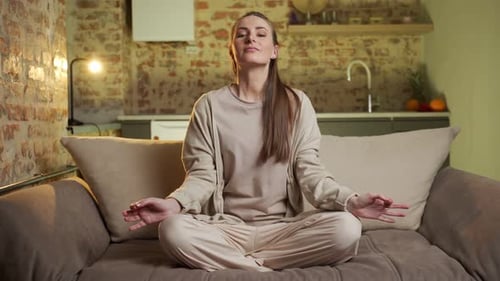 Woman Meditating Peacefully on Couch in Cozy Home