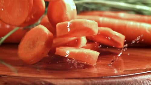Fresh Carrot Slices Falling on Wet Wood