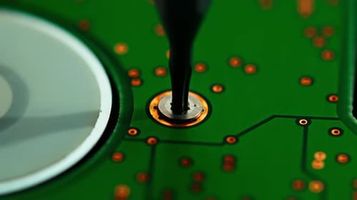 Screwdriver Unscrews Screw on Green Circuit Board