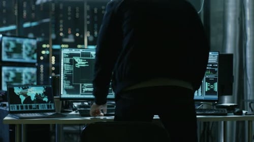 Hooded Programmer Typing Code in Dark Data Center