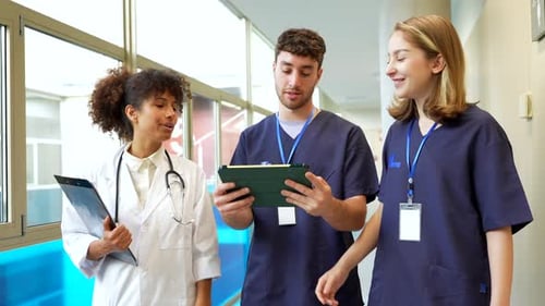 Medical Team Discussing Patient Data on Tablet in Hospital Corridor