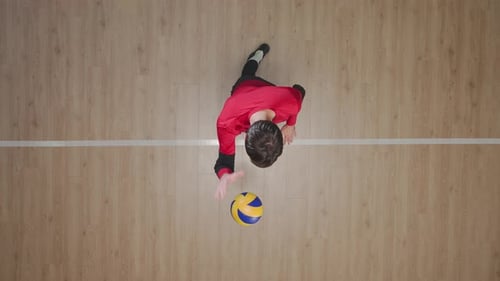 Top View of a Young Man Hitting Ball on Wooden Floor Tossing and Hitting the Ball in Jump
